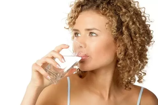La ragazza segue una dieta pigra e beve un bicchiere d'acqua prima di mangiare